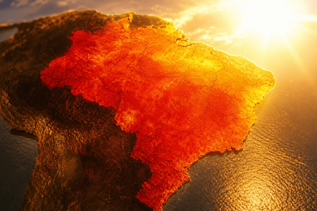 Mapa climático abstrato do Brasil sob forte calor, com áreas em tons de vermelho e laranja, sem textos, números, letras, placas ou logotipos legíveis.