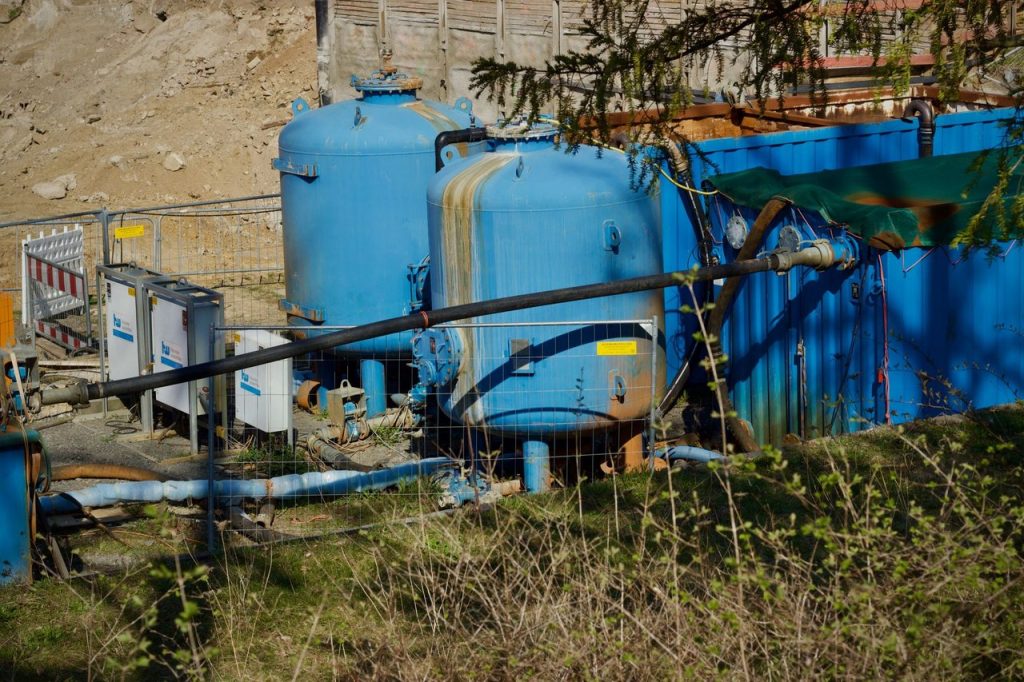Vista de uma estação industrial de tratamento de água, com grandes tanques azuis ao ar livre.