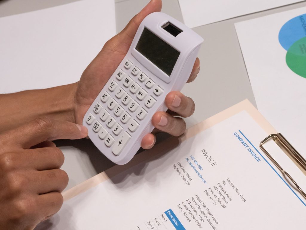 Proposta do governo prevê regularização de dívidas e novas regras para autônomos e MEIs Mãos usando uma calculadora ao lado de uma fatura empresarial sobre uma mesa.